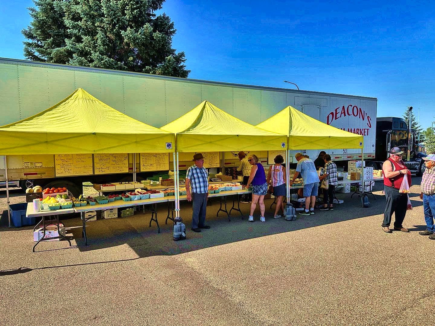 Customers shopping under the yellow Deacon's tents beside the trailer